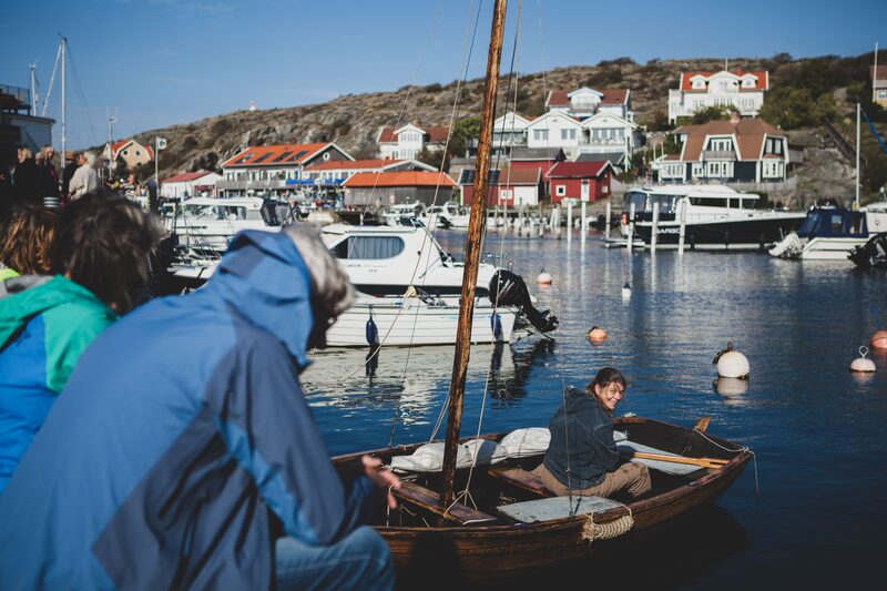 En liten roddbåt i hamnen, med besökare i förgrunden